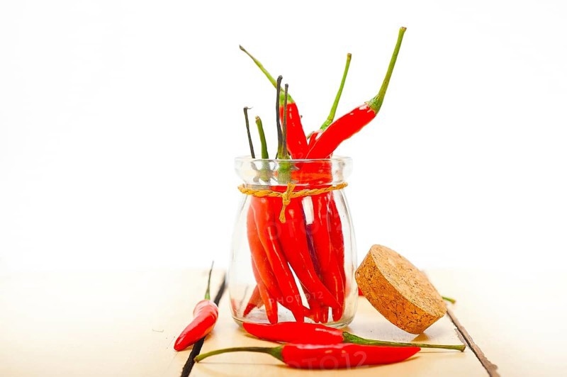 Red chili peppers on a glass jar over white wood rustic table