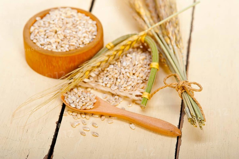 Organic wheat grains over rustic wood table macro closeup