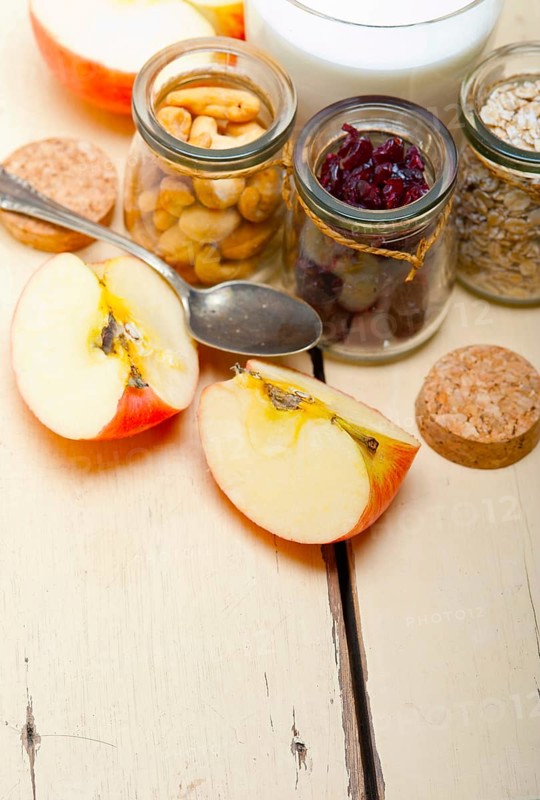 Healthy breakfast ingredients milk oat cashew nuts dried cramberry craisinns