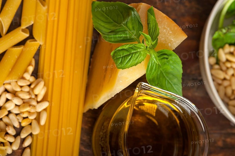 Italian basil pesto ingredients and raw pasta over old wood