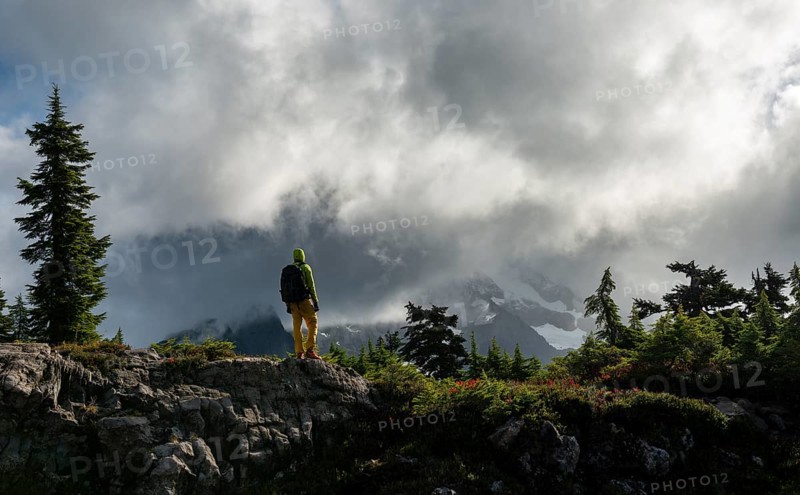 Hiker in front of cloudy Mt. Shuksan with snow and glacier