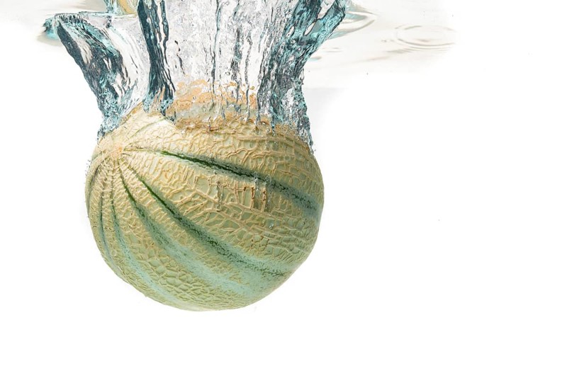 Cantaloupe melon splash and sinking isolated against white background