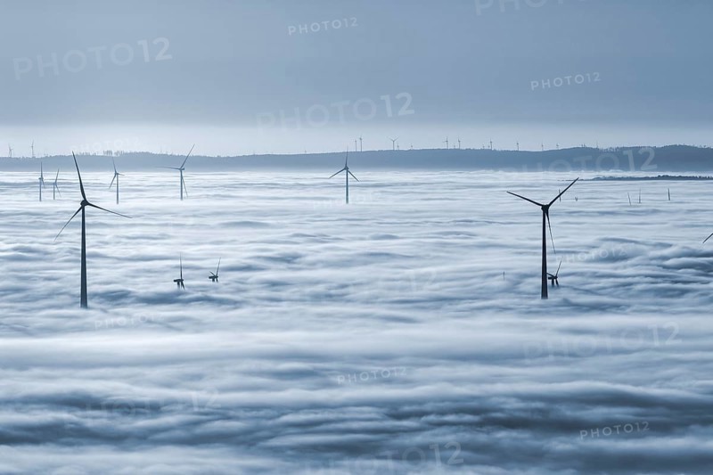 Wind turbines rising from cloud cover