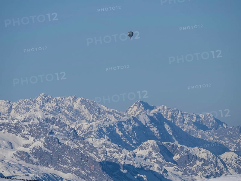Hot air balloons flying over snow-covered Alpine peaks