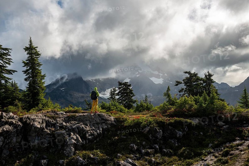Hiker in front of cloudy Mt. Shuksan with snow and glacier