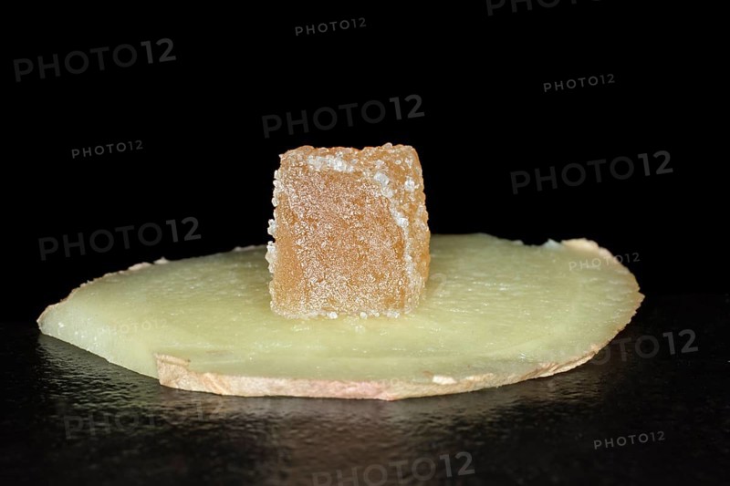 Candied ginger cut into cubes lies on a slice of fresh ginger