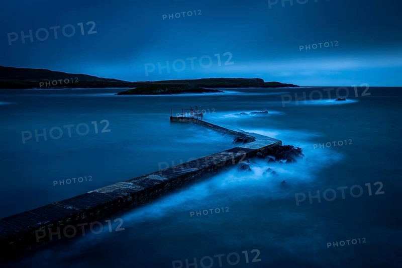 Sea surf on concrete jetty at blue hour