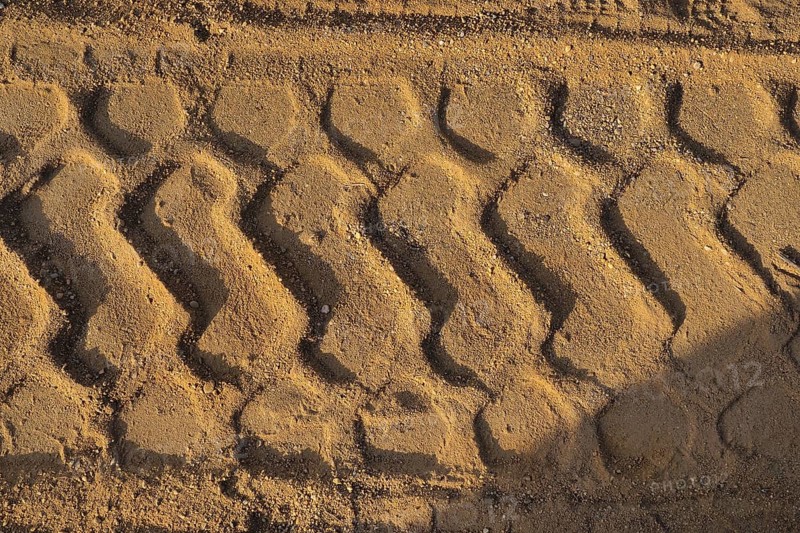 Wide tyre print in the sand from agricultural machine