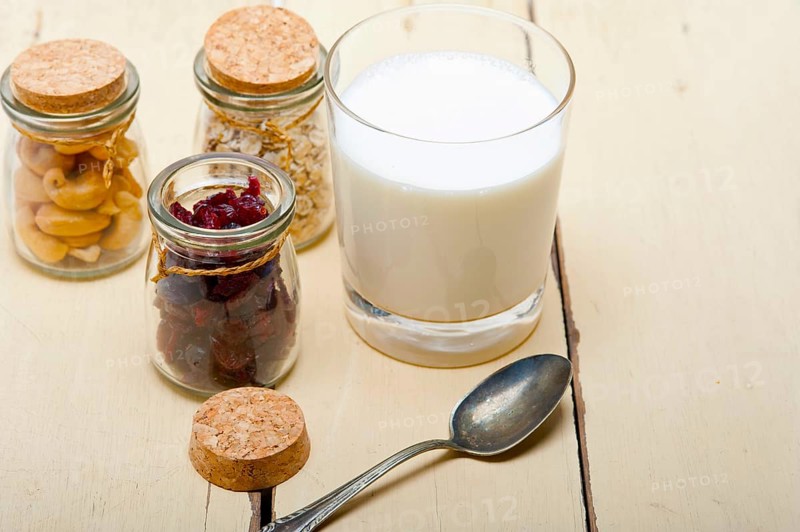 Healthy breakfast ingredients milk oat cashew nuts dried cramberry craisinns