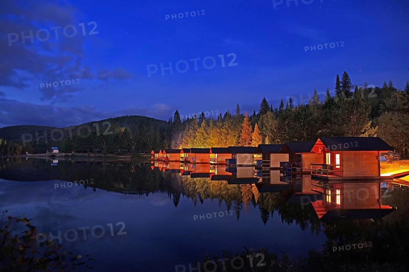 Small wooden holiday cabins at dusk on the shore of a lake