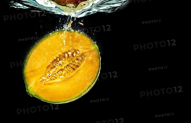 Half of Orange cantaloupe melon sinking and isolated on black background