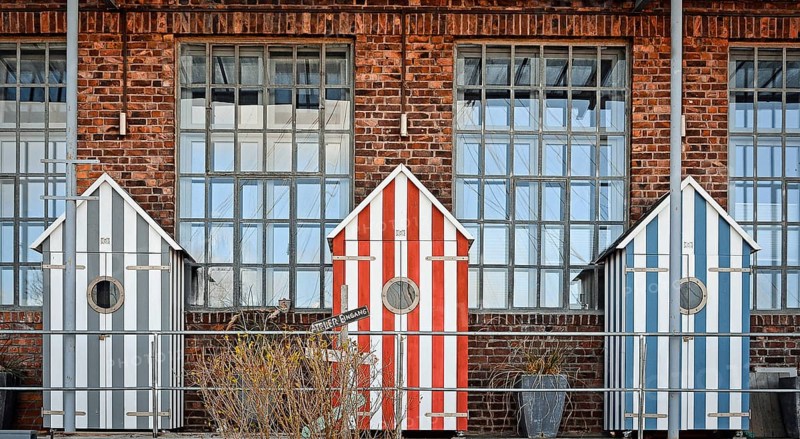 Three bathhouses in front of old industrial building