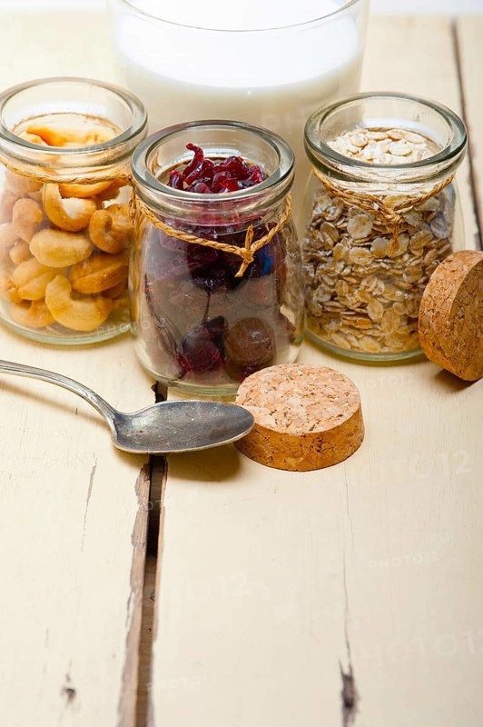Healthy breakfast ingredients milk oat cashew nuts dried cramberry craisinns