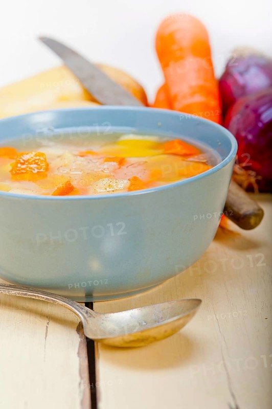 Traditional Italian minestrone soup on a rustic table with ingredients