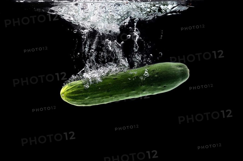 Whole bio cucumber sinking under water against black background