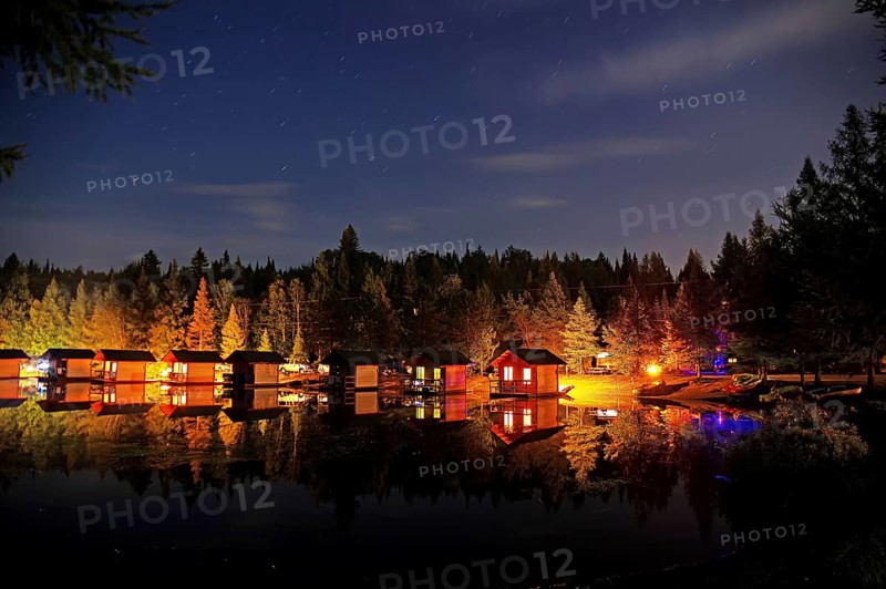 Small wooden holiday cabins at night on the shore of a lake