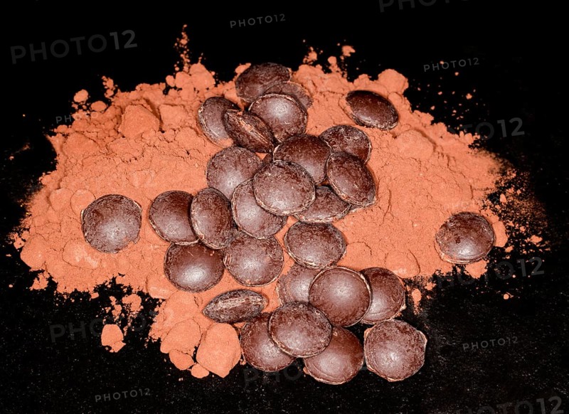 Dark couverture chocolate drops lying on cocoa powder