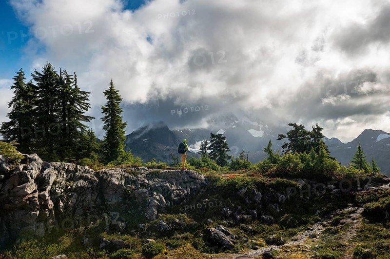 Hiker in front of cloudy Mt. Shuksan with snow and glacier