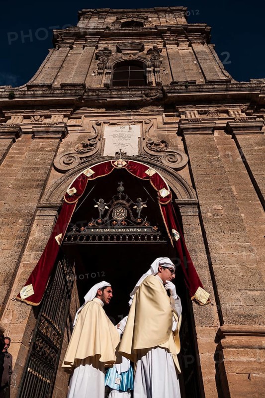 Two young members of a brotherhood dressed for Good Friday at the door of the Cathedral of Enna