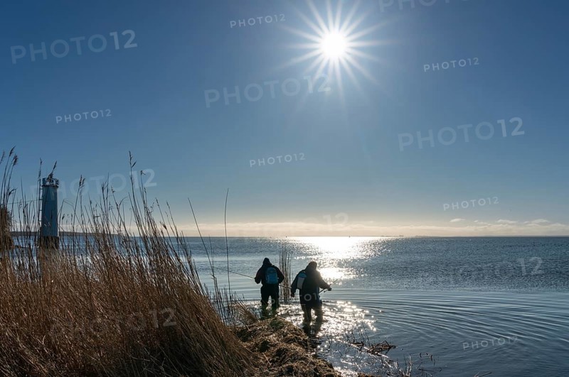 Two anglers in the backlight at the lighthouse of Maltzien on the island of Ruegen