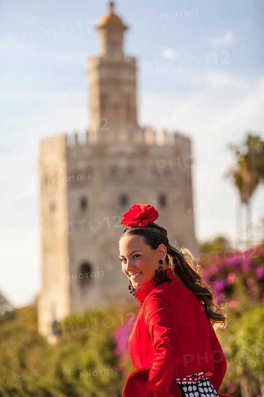 A beautiful young woman in front of the Torre del Oro on her way to the Feria de Abril in Seville