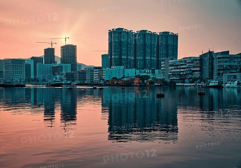 Tall buildings by the sea with reflections at sunset in Macau