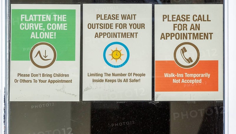 Covid-19 notices about precautions to be taken on glass window of hairdresser shop