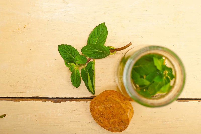 Fresh mint leaves on a glass jarover a rustic white wood table