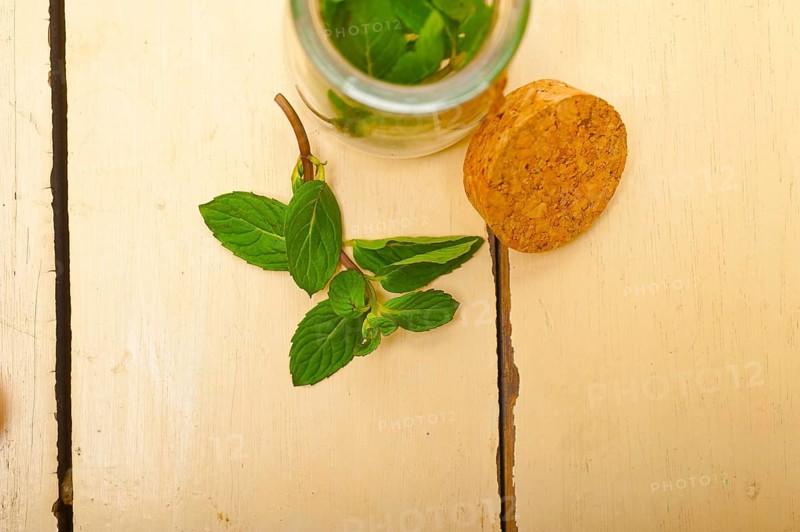 Fresh mint leaves on a glass jarover a rustic white wood table