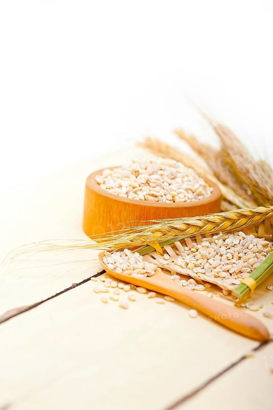 Organic barley grains over rustic wood table macro closeup