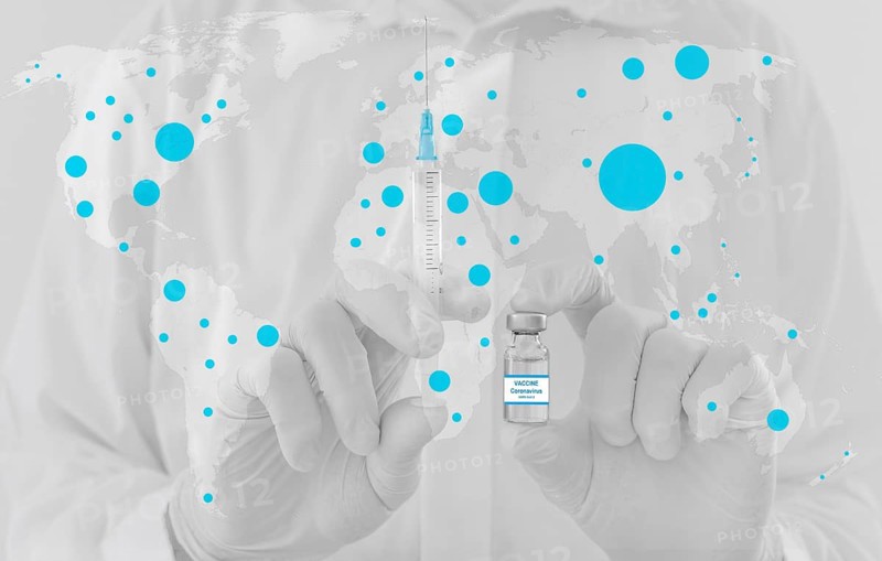 World map and doctor hands holding a vaccine bottle and syringe