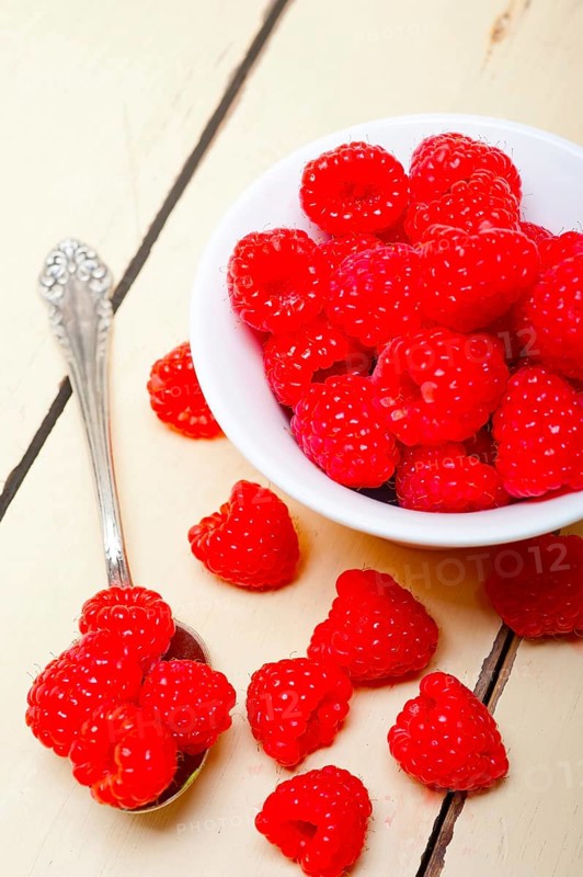 Bunch of fresh raspberry on a bowl and white wood rustic table