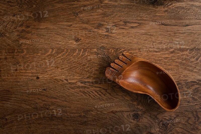 Wooden bowl in the shape of a foot on a wooden table