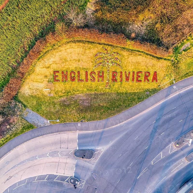 Top Down view of inscription on the flower bed with flowers Welcome in English Riviera from a drone