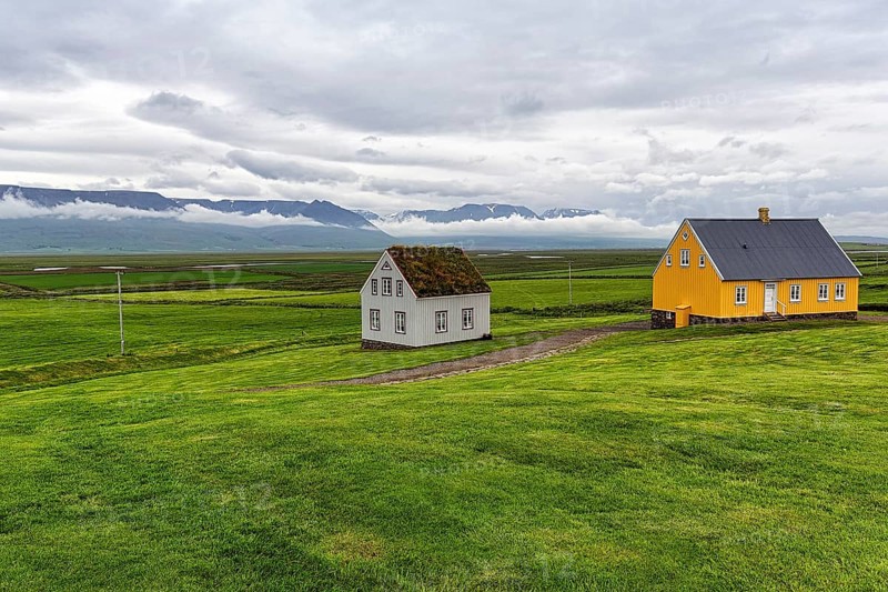 Grass sod house and yellow wooden house in a meadow