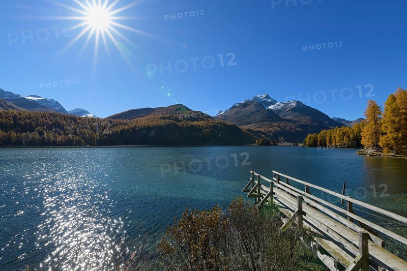 Wooden jetty on lake with sun in autumn