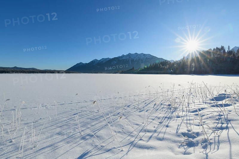 Frozen lake Barmsee with Karwendel mountainrange on morning with sun in winter