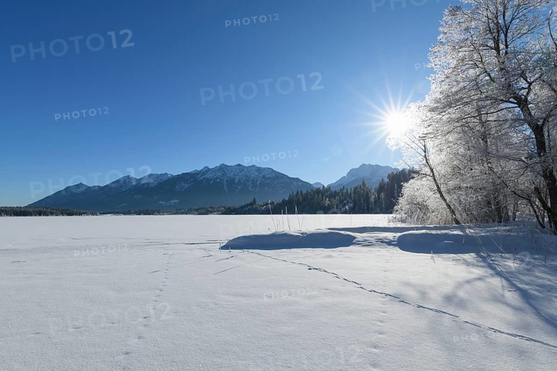 Frozen lake Barmsee with Karwendel mountainrange on morning with sun in winter