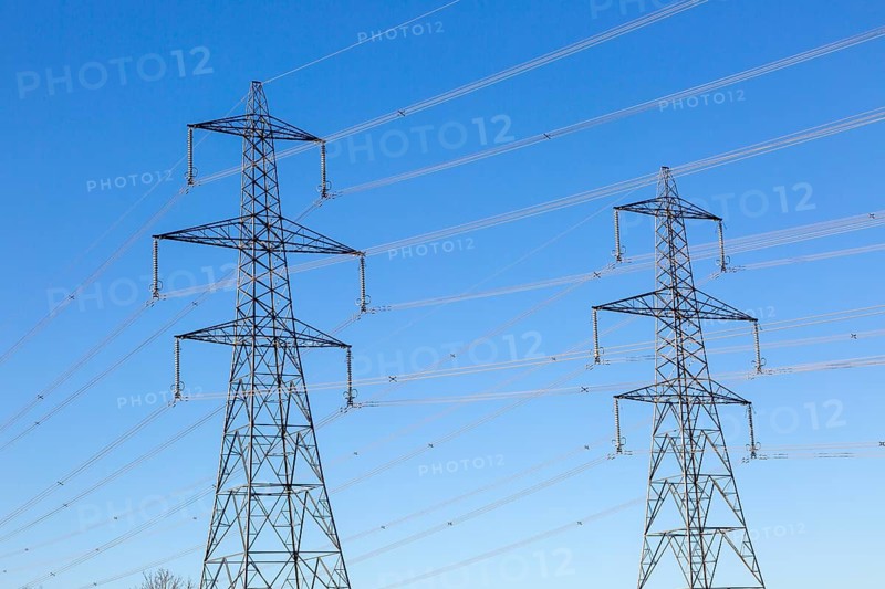Electrical pylons and high voltage electricity transmission power lines from Sizewell nuclear power station against blue sky