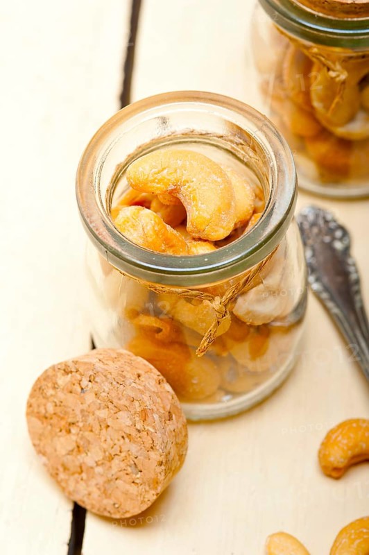 Cashew nuts on a glass jar over white rustic wood table