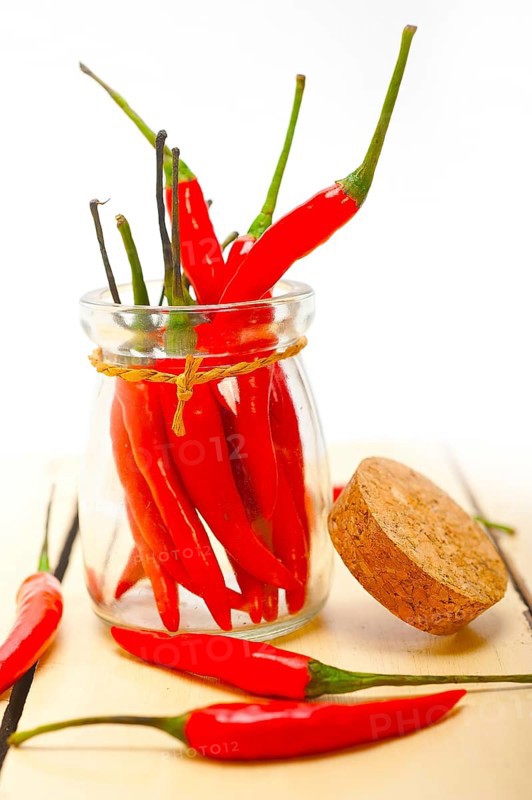 Red chili peppers on a glass jar over white wood rustic table