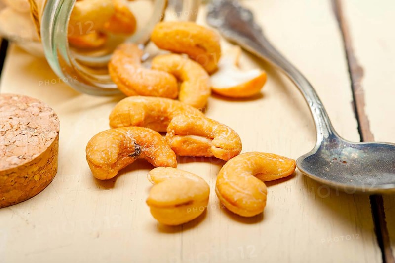 Cashew nuts on a glass jar over white rustic wood table