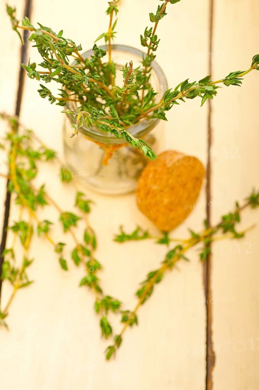 Fresh thyme on a glass jar over a white wood rustic table