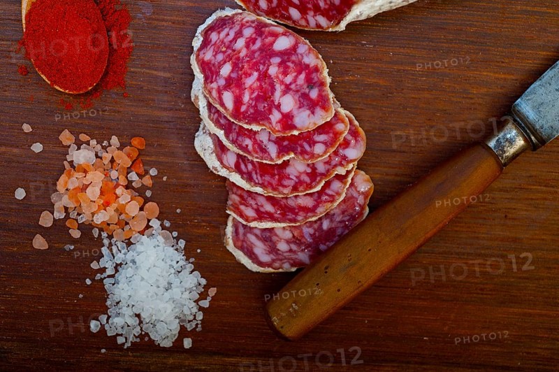 Traditional Italian salame cured sausage sliced on a wood board