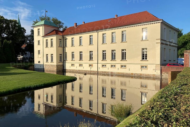 View of classicist castle Westerholt with reflection of building in historical moat