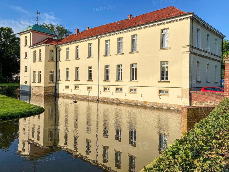 View of classicist castle Westerholt with reflection of building in historical moat