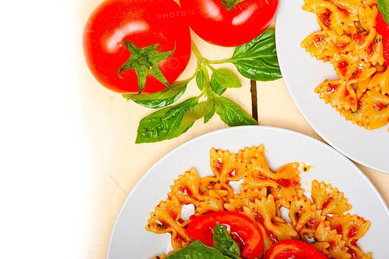 Italian pasta farfalle butterfly bow-tie with tomato basil sauce over white rustic wood table