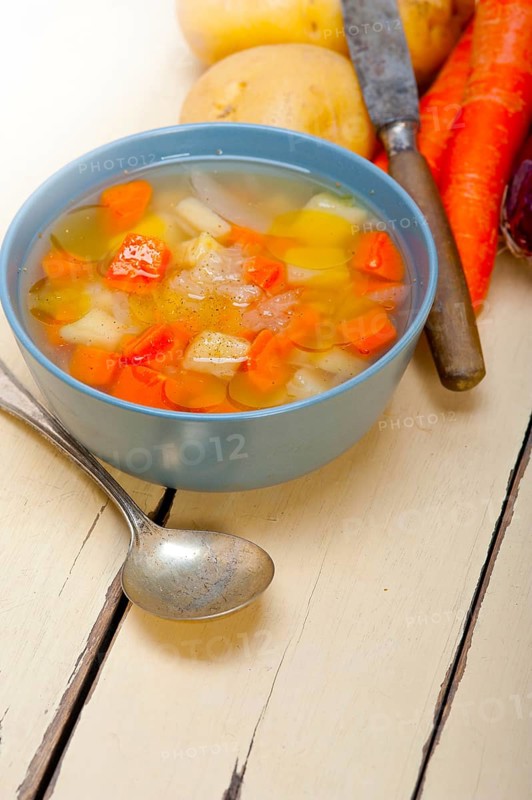 Traditional Italian minestrone soup on a rustic table with ingredients