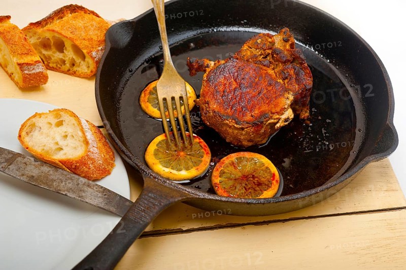 Pork chop seared on iron skillet with lemon and spices seasoning