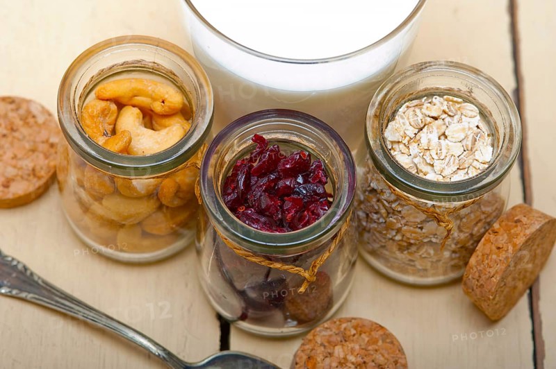 Healthy breakfast ingredients milk oat cashew nuts dried cramberry craisinns